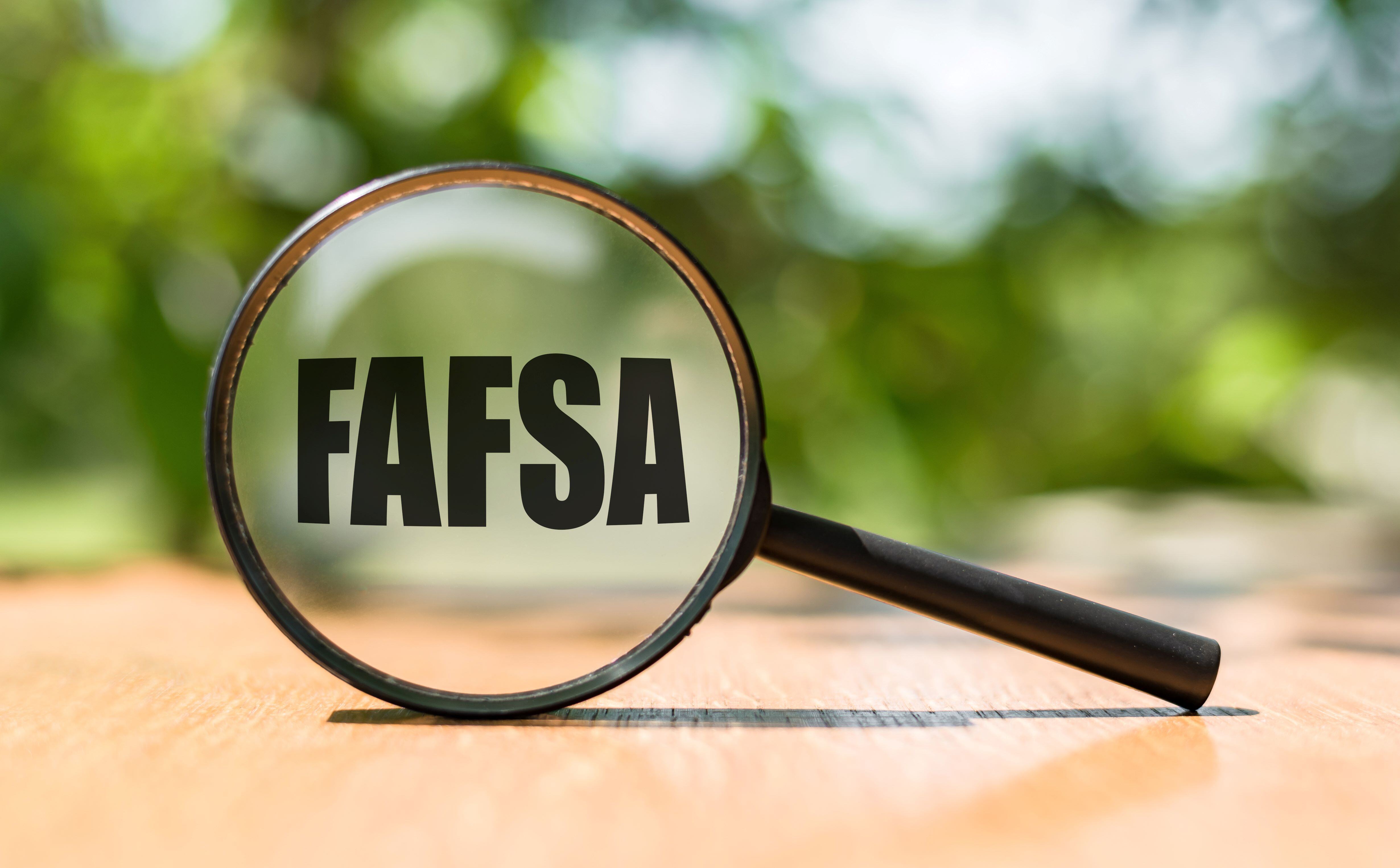 a hand-held magnifying glass with the word FAFSA written on the glass 